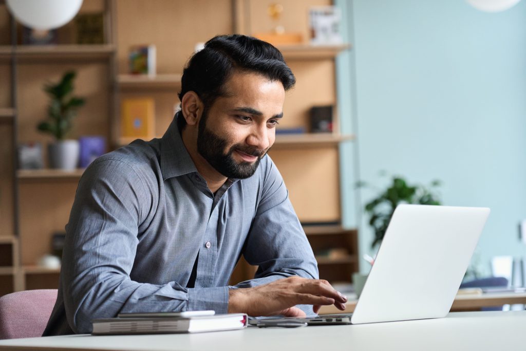 smartly dresses man smiling at a laptop screen